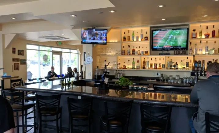 Digital signage screens at a bar displaying news update feed from Pickcel's digital signage TOI news app